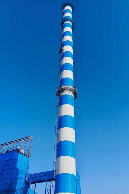Blue-and-white industrial RCC chimney beside plant steelwork.
