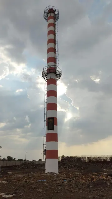 Red-and-white RCC chimney and access platforms at a site under cloudy skies.