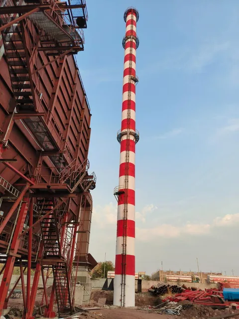Red-and-white industrial chimney beside a plant steel structure.