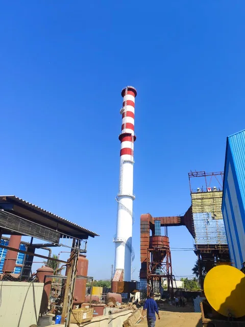 Red-and-white chimney within an industrial plant yard.